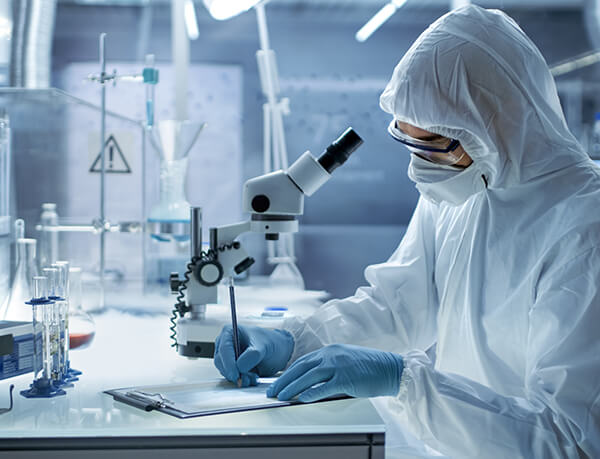 Technician Lab Technician in Full Coveralls with Microscope Taking Notes